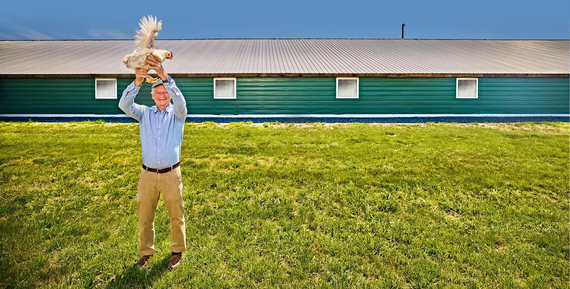 Jim Perdue holding a chicken outside of his farm