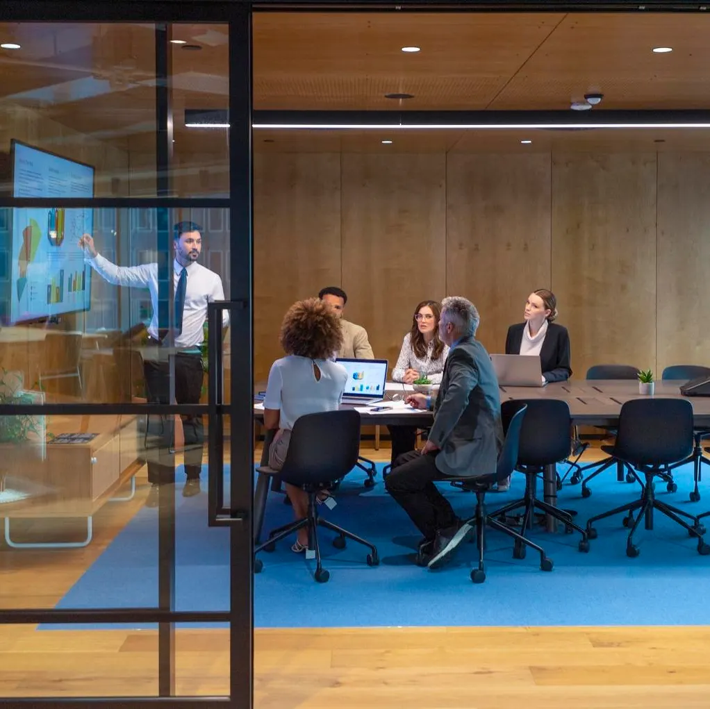 Man giving a data presentation on a tv in a board room.