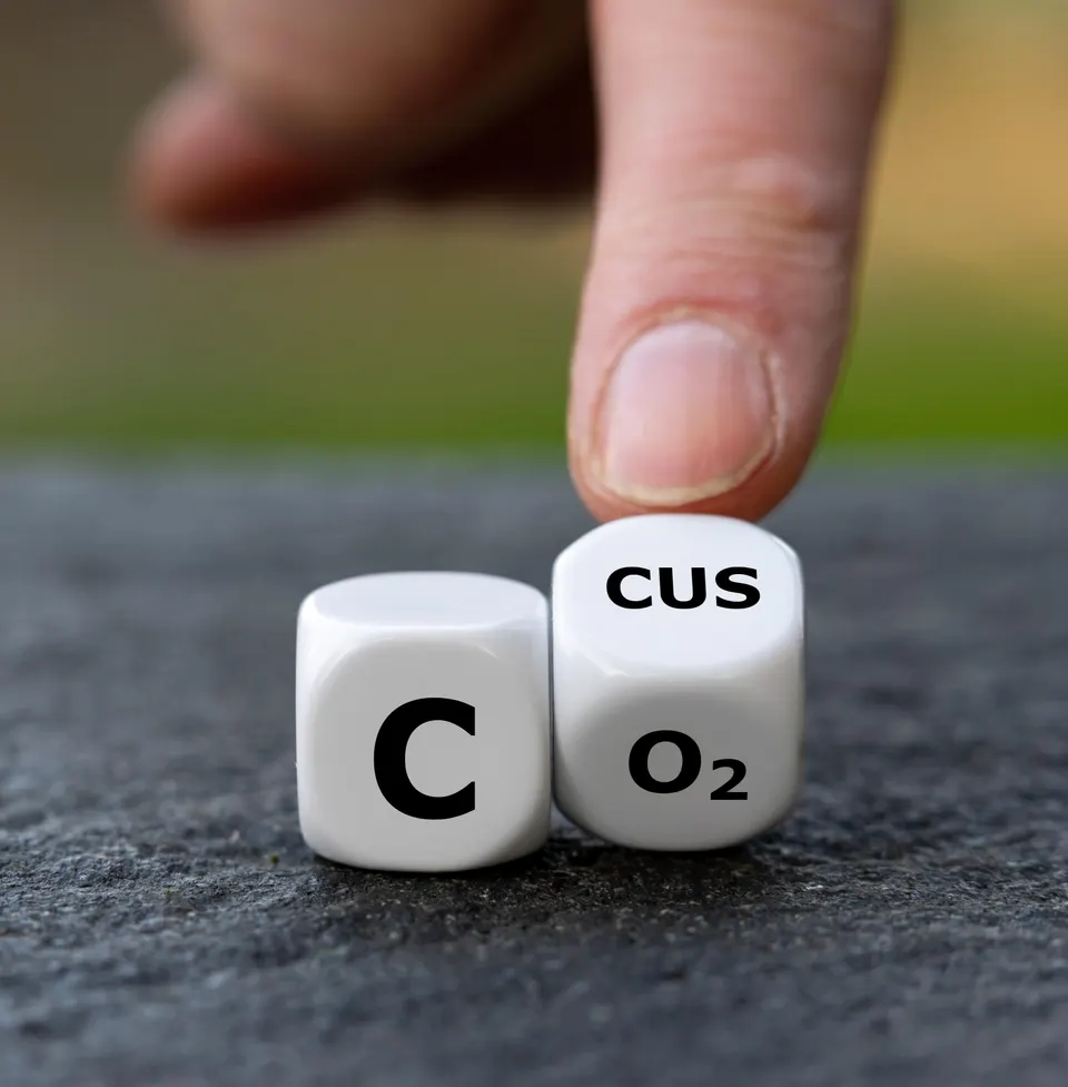 Symbol for carbon capture, utilization and storage (CCUS). Hand turns dice and changes the expression Co2 to CCUS.