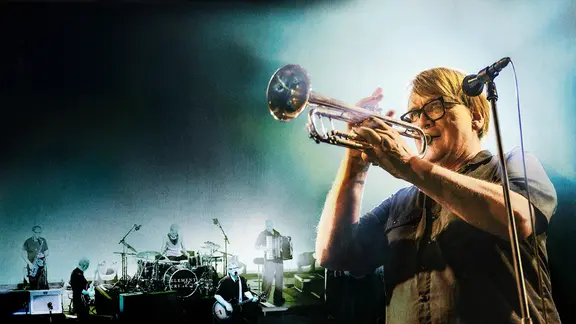 Sven Regener spielt Trompete bei einem Konzert. Im Hintergrund ist die Band Element of Crime zu sehen.