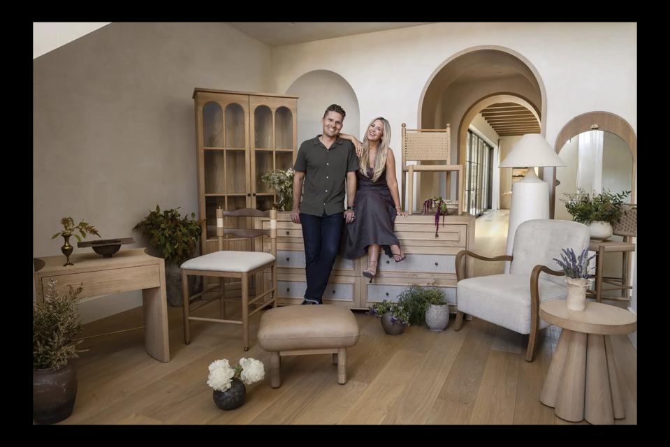 A photo of the founders of Le Maé surrounded by many of their original furniture designs.