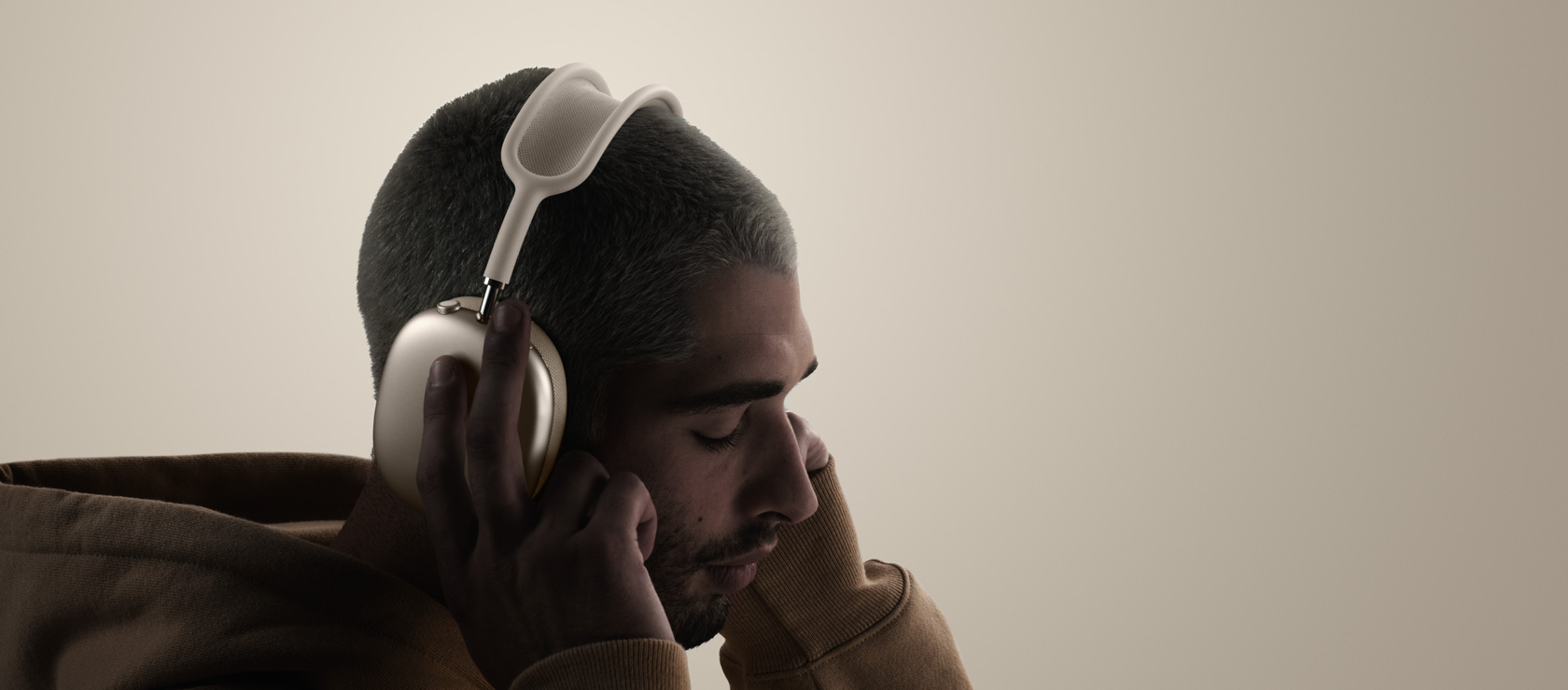 Un hombre con sus manos en las almohadillas de sus AirPods Max.