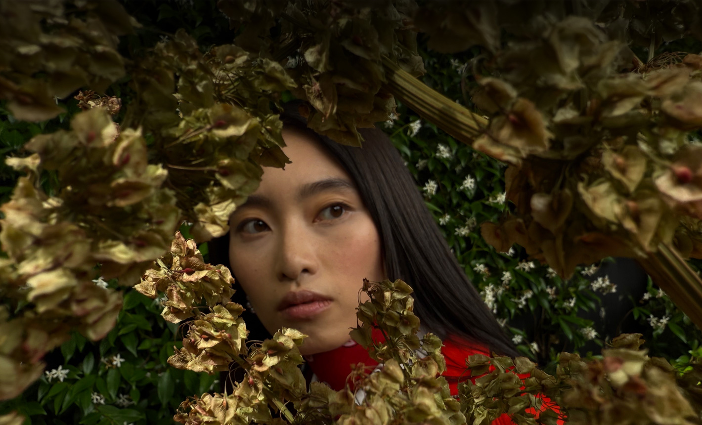 Close-up van een vrouw die wordt omringd door bladeren