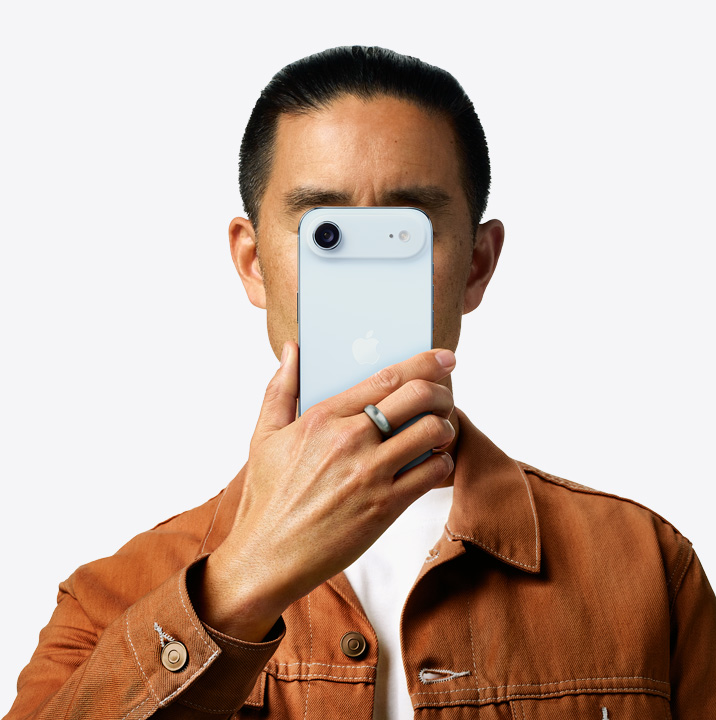 Uma pessoa segurando um iPhone Air na cor azul-céu em frente ao rosto, mostrando a parte de trás e o sistema de câmera dupla no canto superior esquerdo