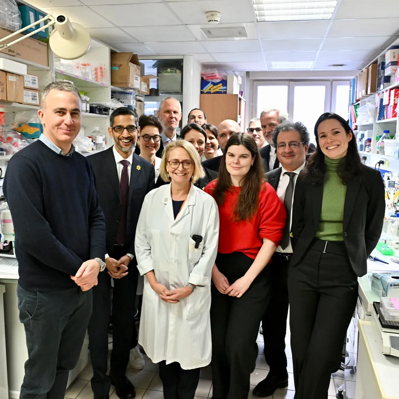 Google CEO Sundar Pichai and partners standing in a lab and smiling at the camera